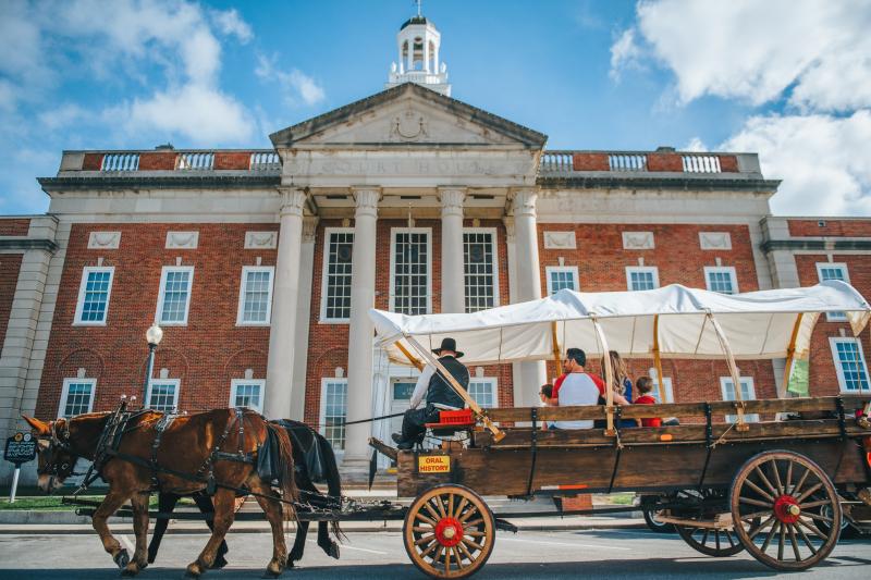 Covered wagon pulled by mules in front of Historic Courthouse